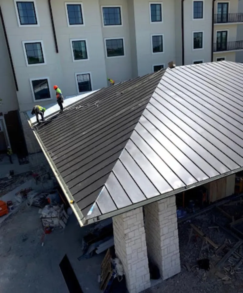 Crew installing standing seam metal roof panels on a commercial project in Brookhaven